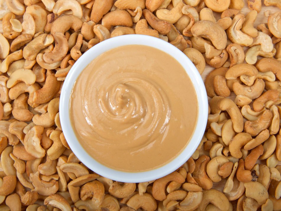 White,Bowl,With,Fresh,Cashew,Butter,Surrounded,By,Cashew,Nuts.